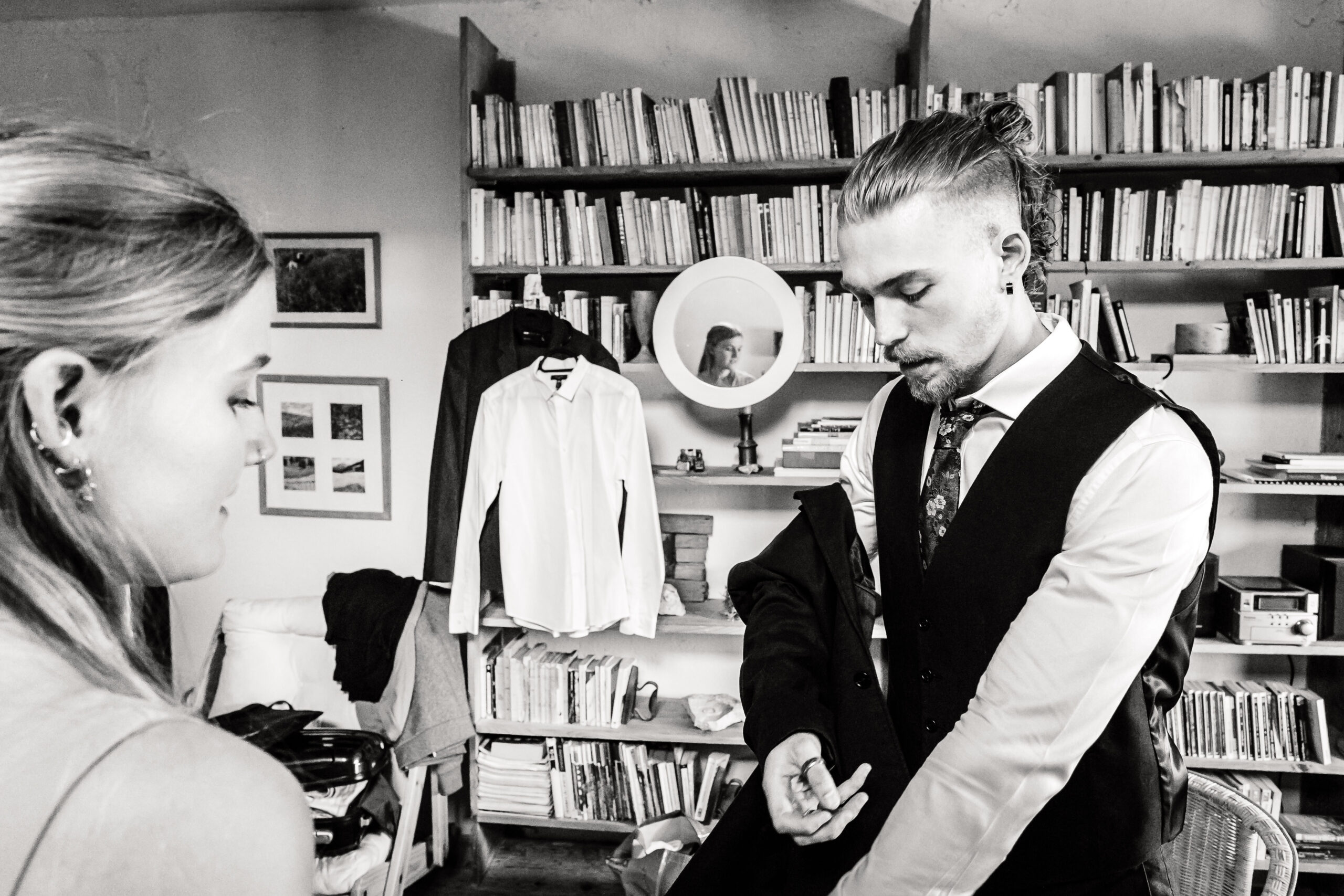 Le marié pendant les préparatifs se fait aider par sa sœur pour enfiler son costume, photo prise par Florian Fauvarque photographe de mariage en Isère