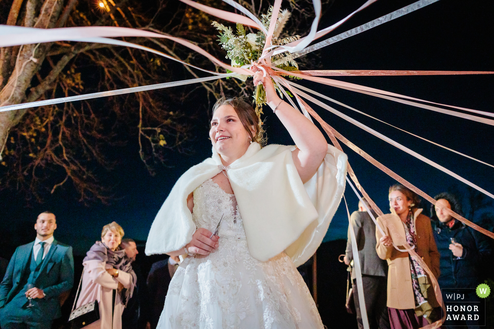 La mariée s'apprête à couper les rubans lors du jeu des rubans, photo prise par Florian Fauvarque photographe de mariage. Élu WPJA Honor Award par WPJA