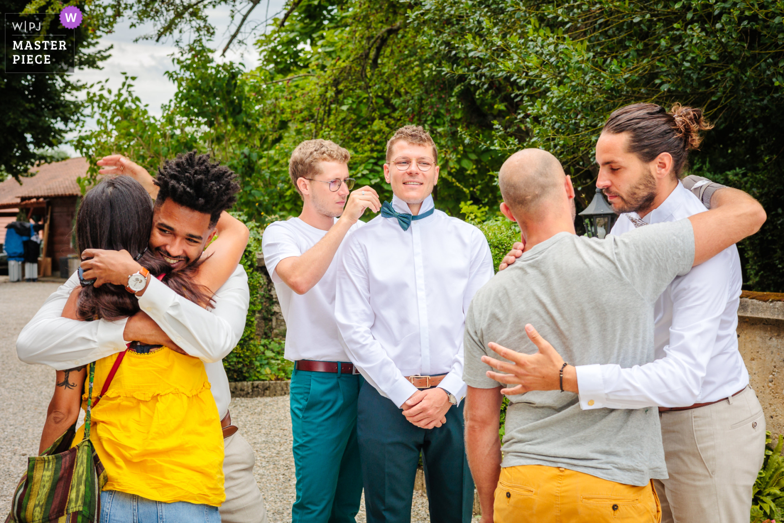 Le marié fait aider avec son nœud de papillon pendant que les témoins accueil les invités, photo prise par Florian Fauvarque photographe de mariage. Élu WPJA Master Piece Purple par WPJA