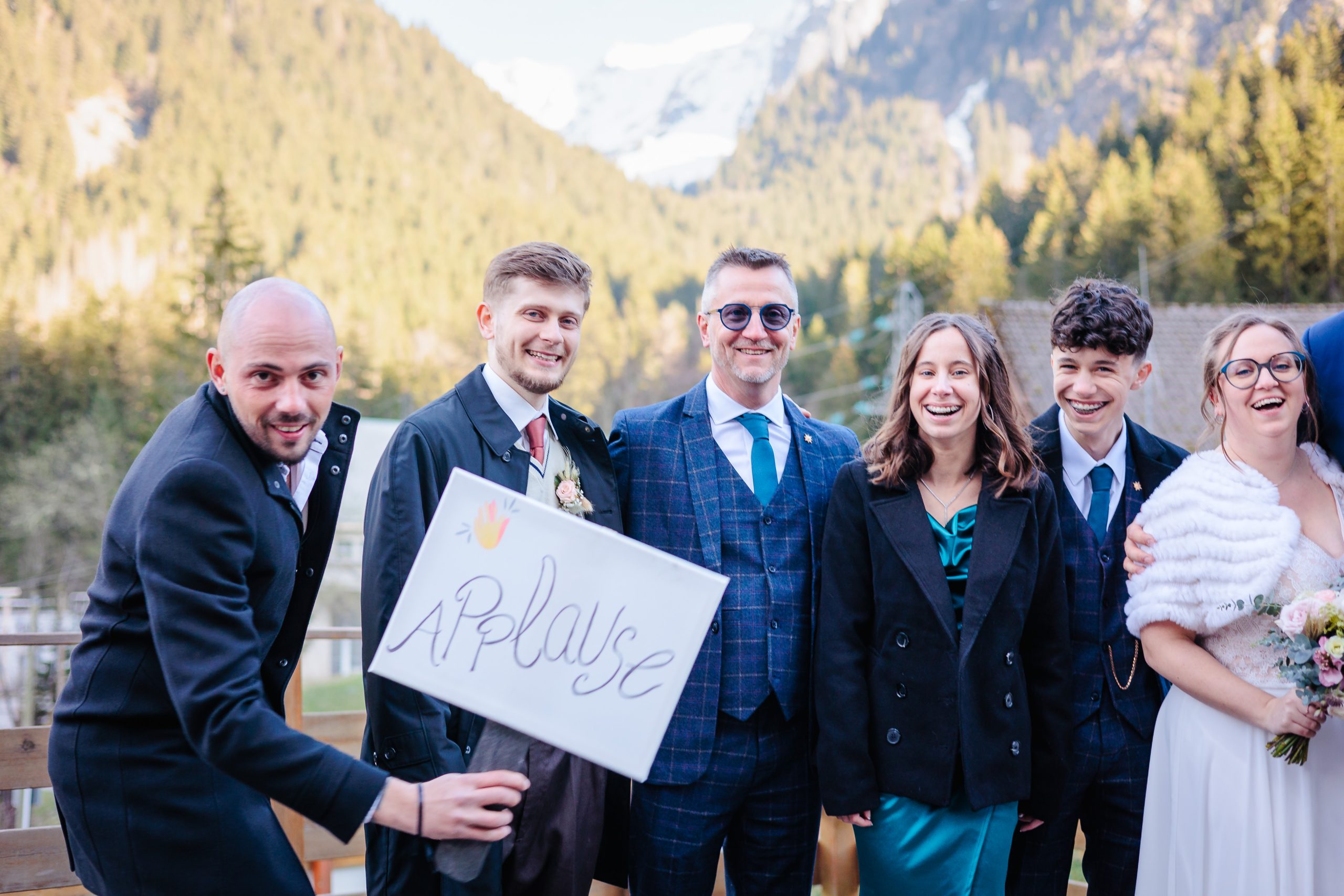 Photo de groupe avec une pancarte Applause, photo prise par Florian Fauvarque photographe de mariage à Grenoble et en Isère