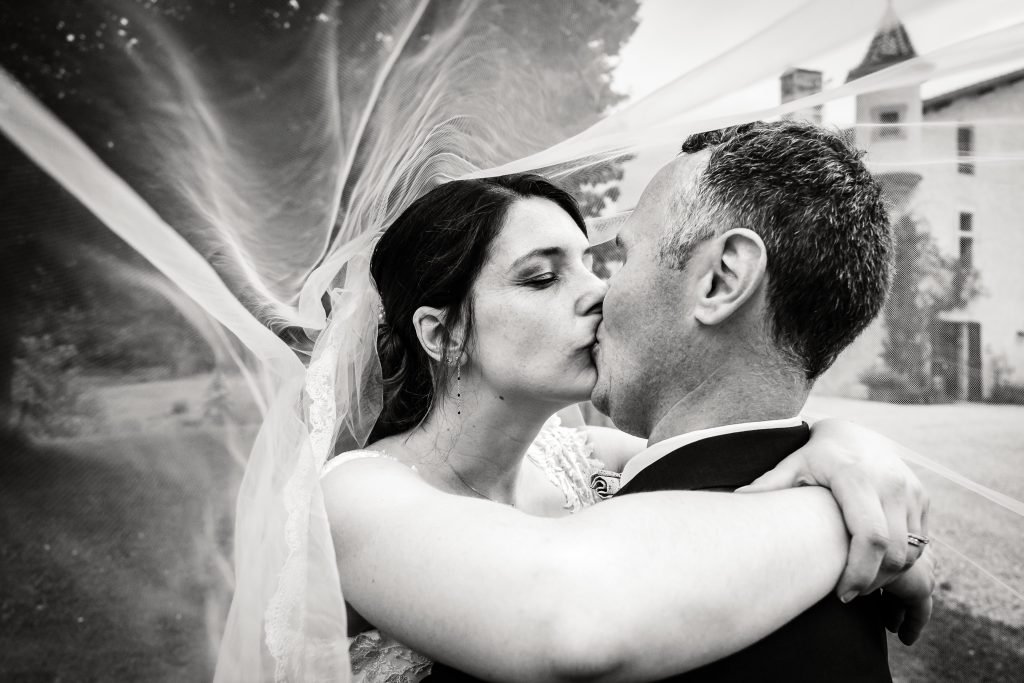 Les mariés s'embrassent sous le voile de la mariée, photo prise par Florian Fauvarque photographe de mariage à Grenoble et en Isère