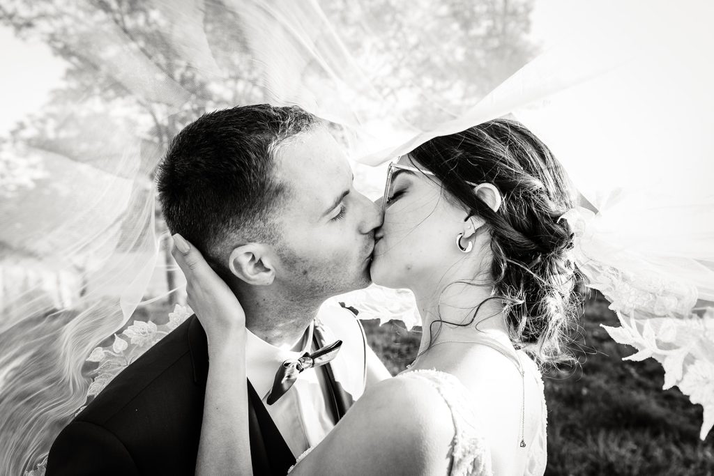 Baiser sous le voile de la mariée, photo prise par Florian Fauvarque photographe de mariage à Grenoble et en Isère