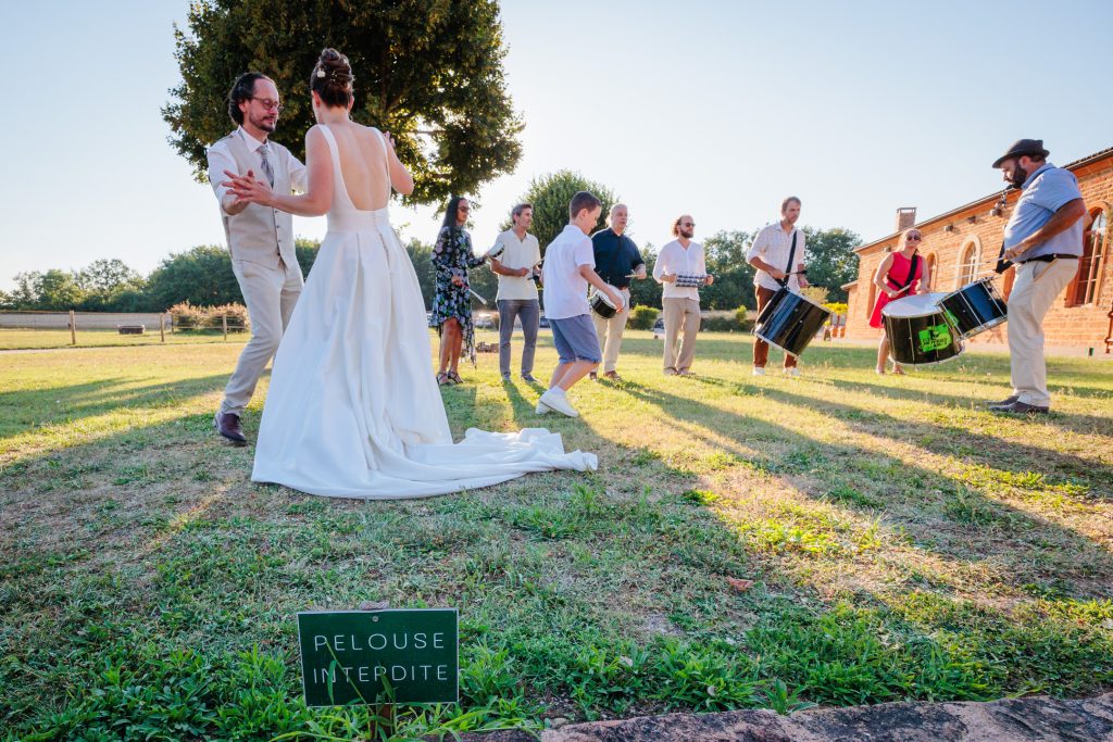 Les mariés dansent dans l'herbe devant un panneau interdit, photo prise par Florian Fauvarque photographe de mariage à Grenoble en Isère