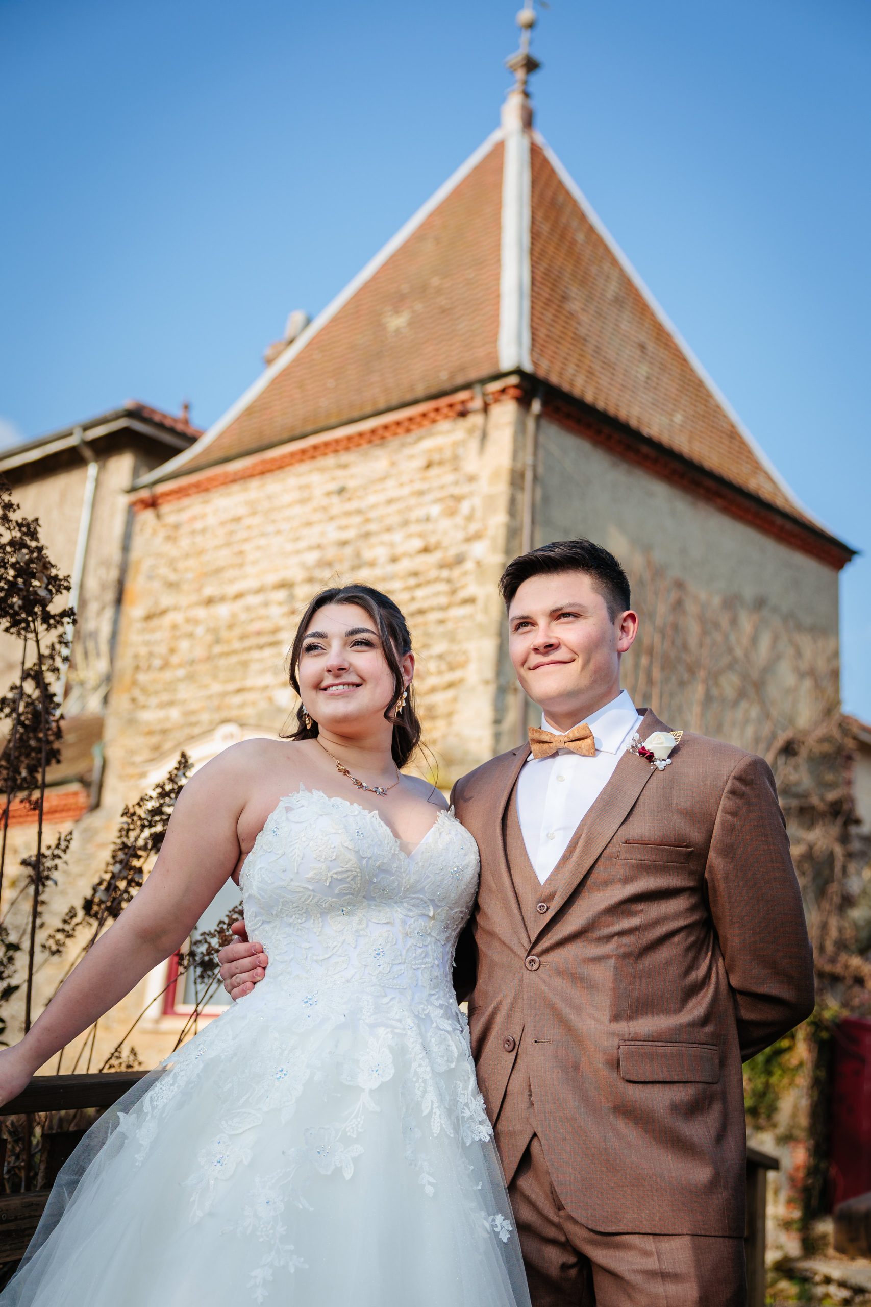 Mariée et marié souriant devant un bâtiment historique, photo prise par Florian Fauvarque photographe de mariage à Grenoble et en Isère