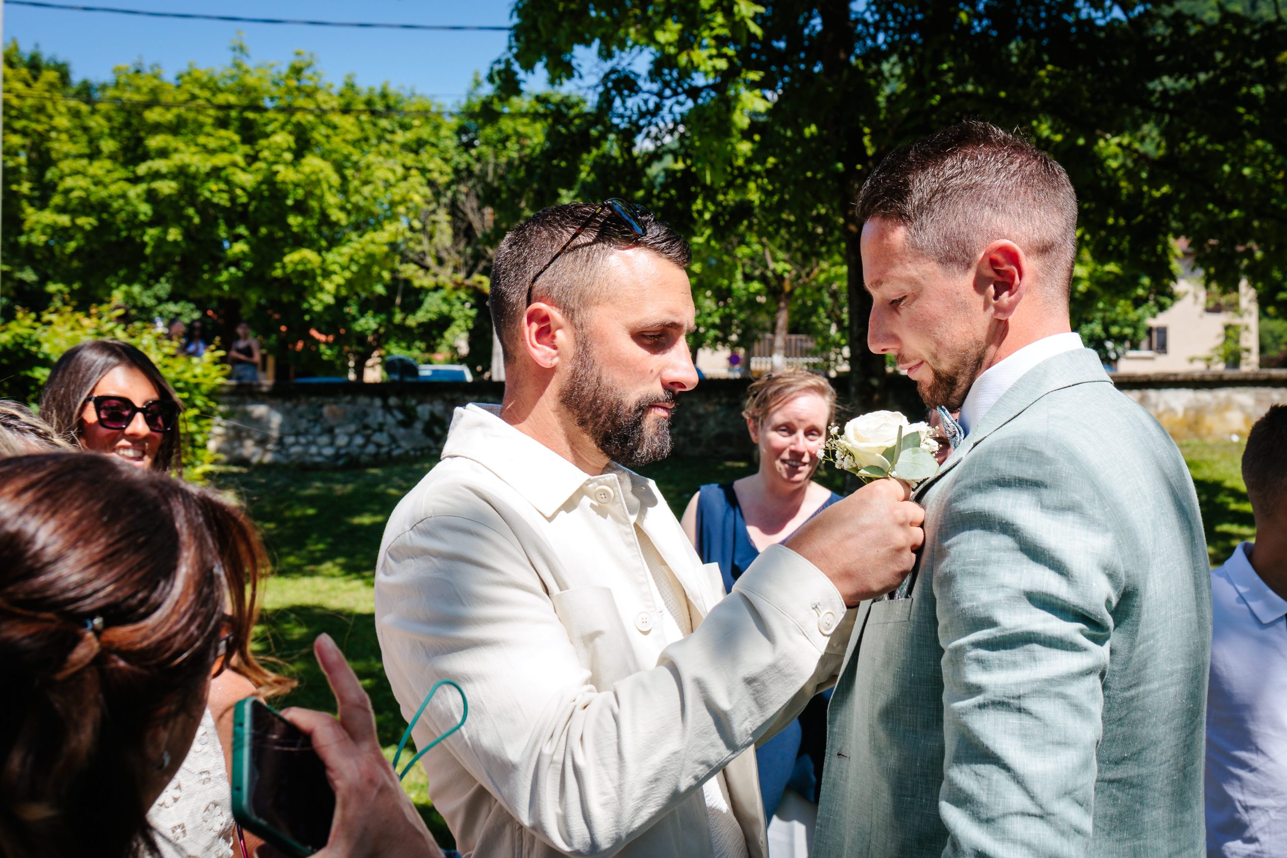 Invités préparant le marié pour le mariage à l'extérieur, photo prise par Florian Fauvarque photographe de mariage à Grenoble et en Isère