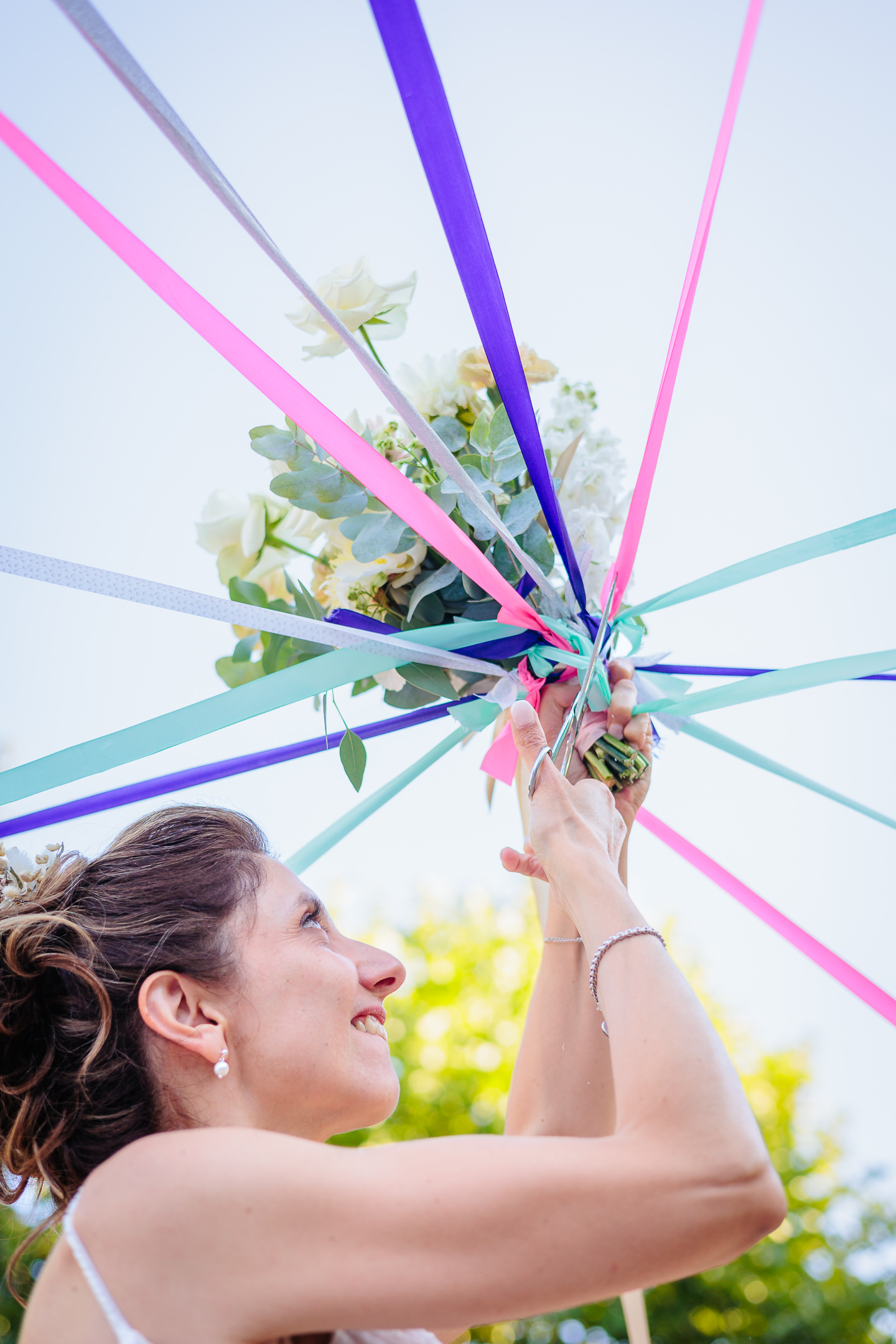 Mariée coupant les rubans pour le jeu du bouquet, photo prise par Florian Fauvarque photographe de mariage à Grenoble et en Isère