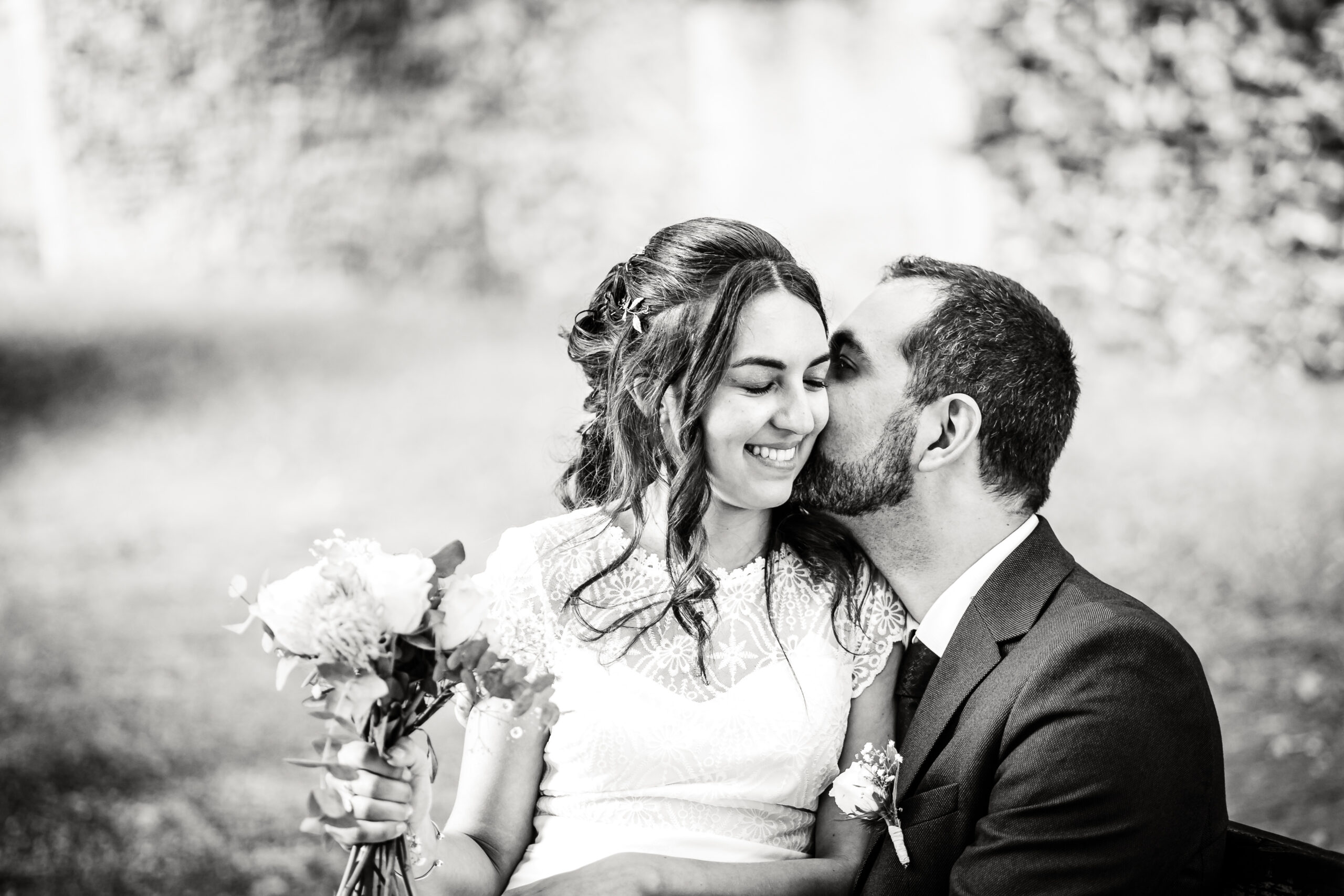Mariage romantique en plein air un couple assis souriant, photo prise par Florian Fauvarque photographe de mariage à Grenoble et en Isère