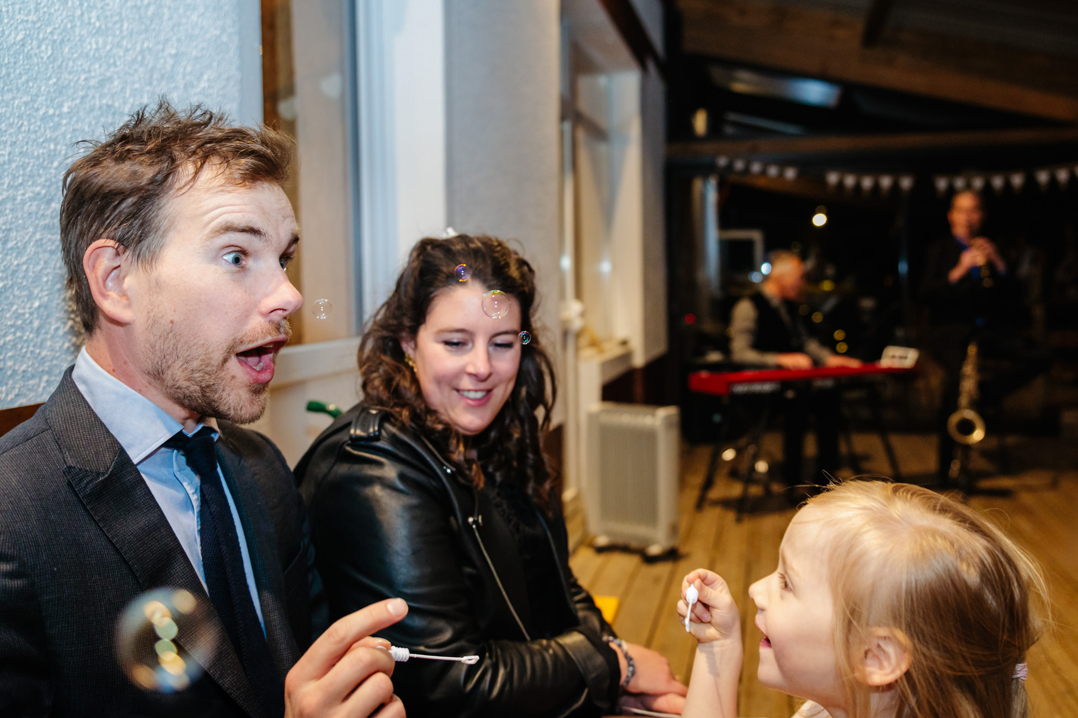 Homme amusé soufflant des bulles avec une fille lors d'un mariage, photo prise par Florian Fauvarque photographe de mariage à Grenoble et en Isère