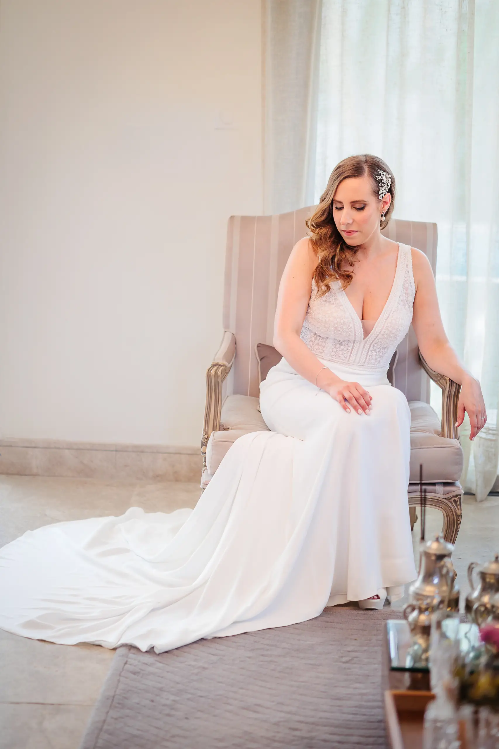 Mariée rêveuse assise sur un fauteuil élégant, robe blanche, photo prise par Florian Fauvarque photographe de mariage à Grenoble et en Isère
