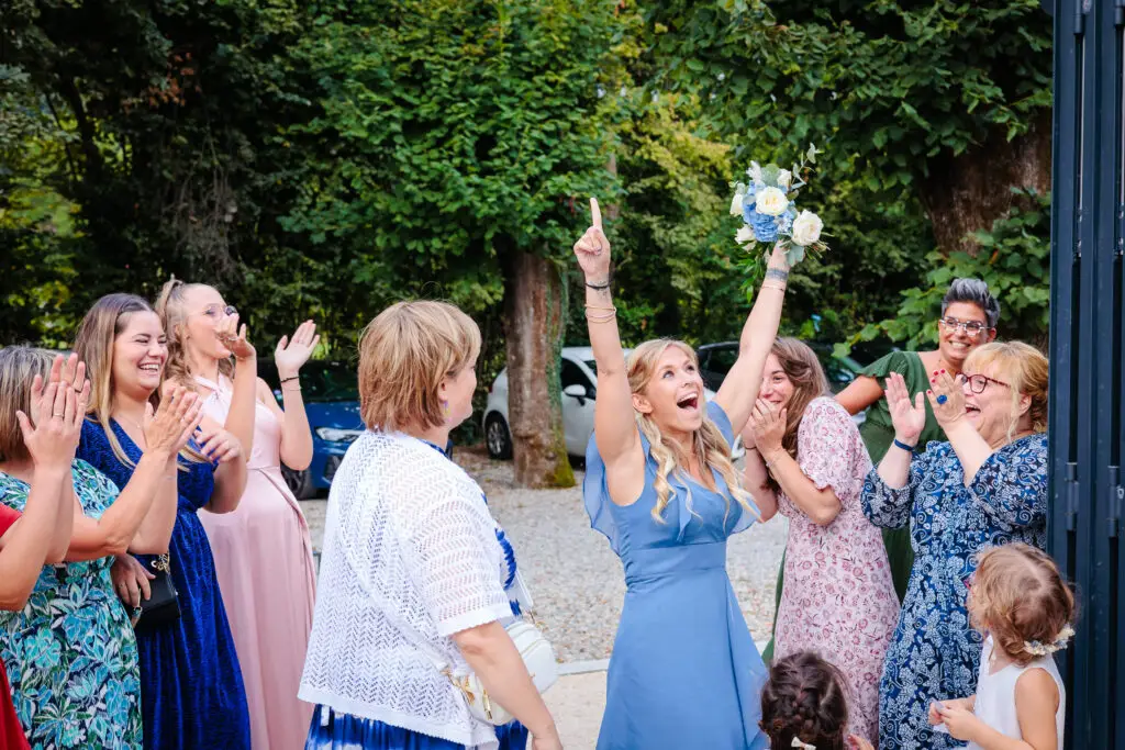 Mariée lançant son bouquet entourée d'invités réjouis, photo prise par Florian Fauvarque photographe de mariage à Grenoble et en Isère
