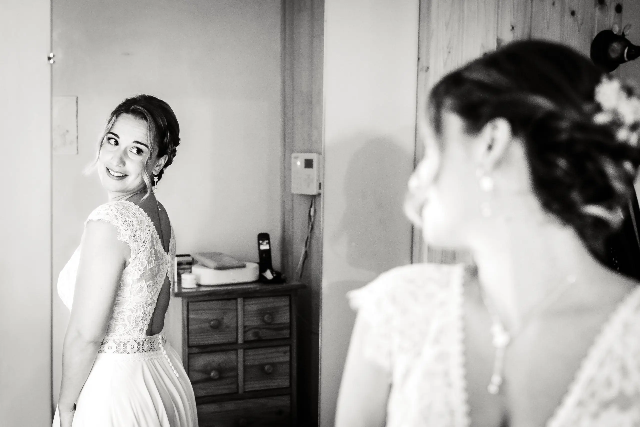 Mariée souriante se préparant dans le miroir, photo prise par Florian Fauvarque photographe de mariage à Grenoble et en Isère