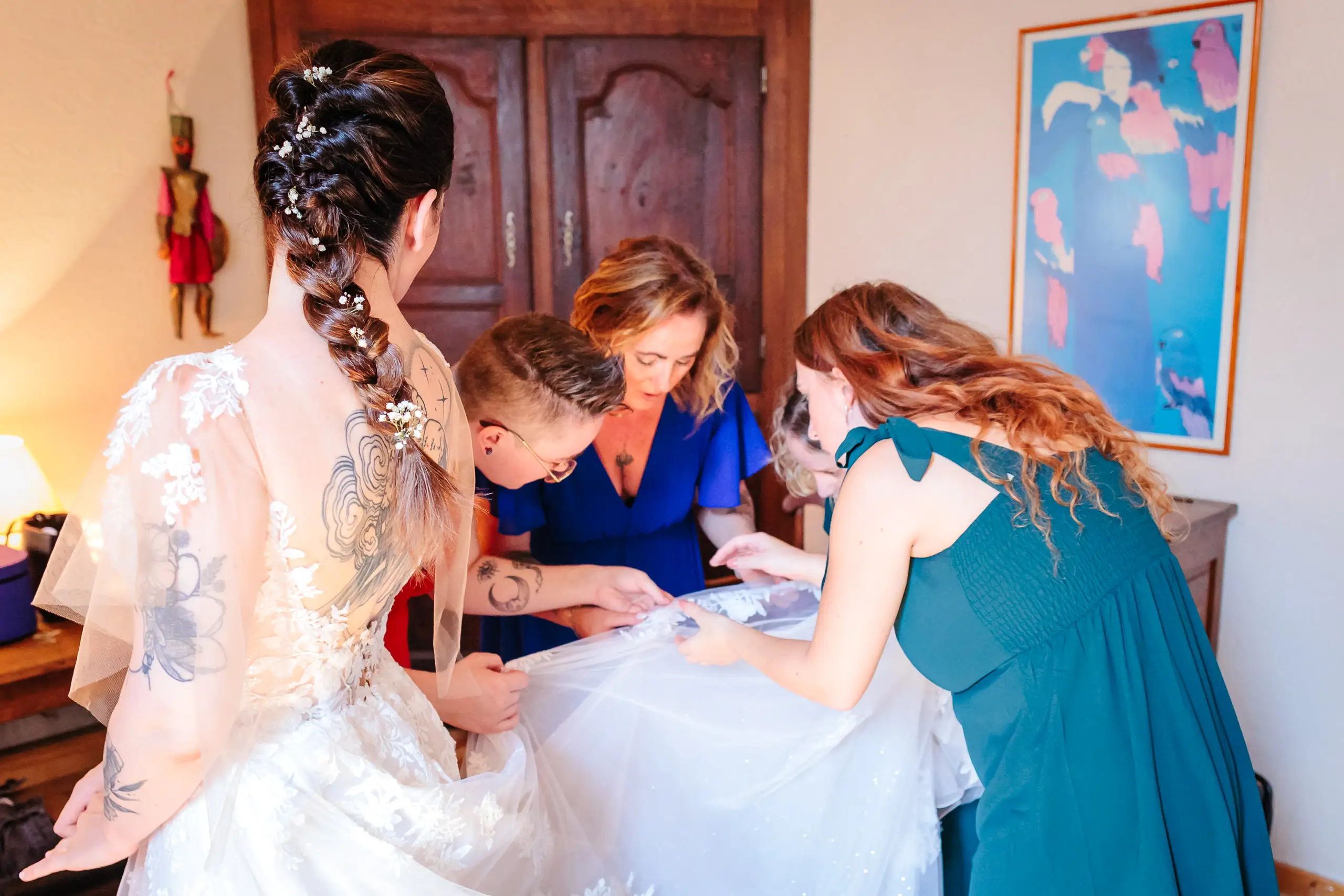 Mariée entourée par des demoiselles d'honneur préparant la robe, photo prise par Florian Fauvarque photographe de mariage à Grenoble et en Isère