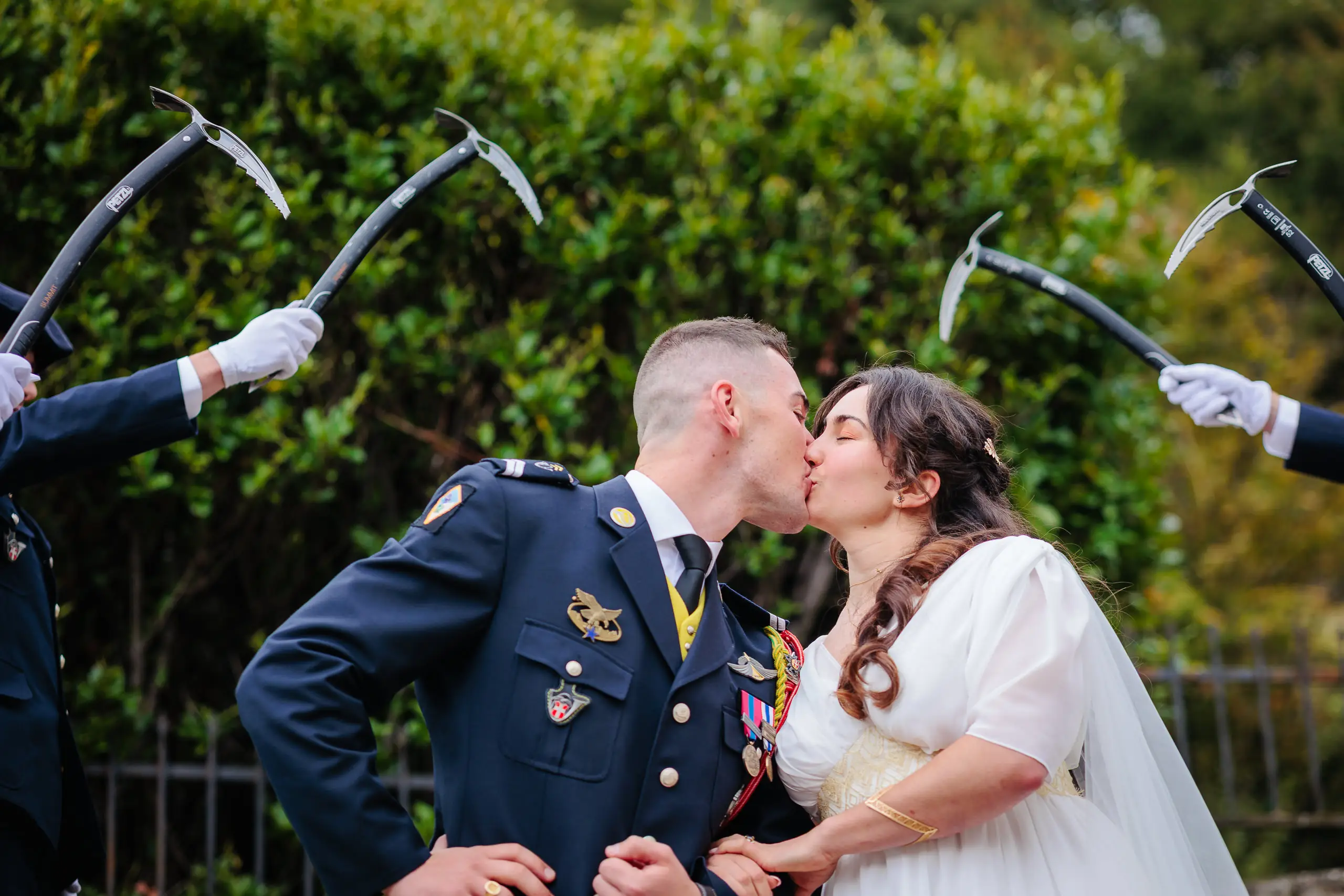 Couple de mariés s'embrassant sous une haie d'honneur militaire, photo prise par Florian Fauvarque photographe de mariage à Grenoble et en Isère